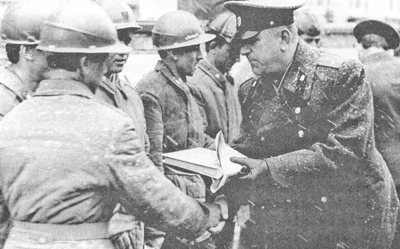  Командир полка полковник Я. Тасоев вручает ценные подарки военным строителям. 