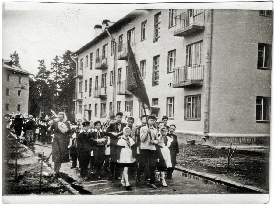 Уже через четыре года в новом поселке выросла улица Ленинская. 1 мая 1962 года — идут ученики первой поселковой школы (позднее — вечерняя школа). Фотограф — В.А.Беляев